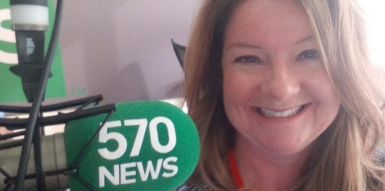 Lisa pictured smiling beside her microphone with the 570 news logo on it