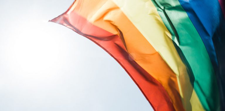 Pride rainbow flag blowing in the wind against the sky
