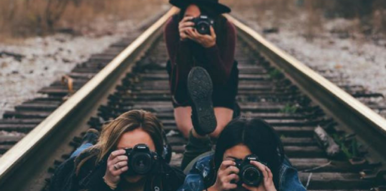 three girls holding cameras in front of their faces