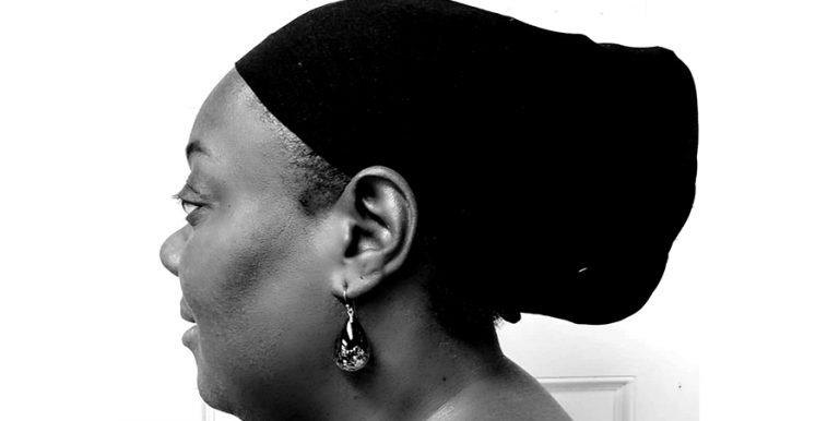 A black and white close-up of Lisa, side view. She's wearing a black scarf over her hair.