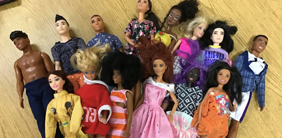 A bundle of barbies, all shapes and skin tones, lying on a table