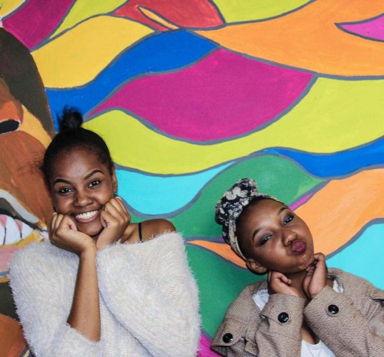 two-bipoc-youth-girls-making-faces-with-their-hands-under-their-chins