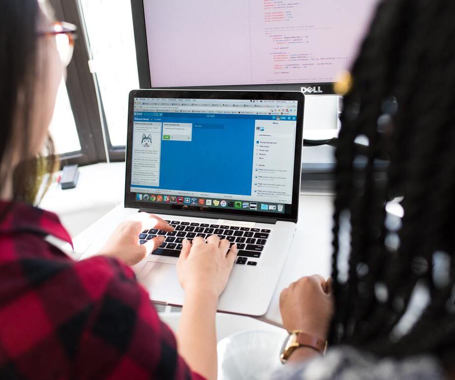 two young women looking at coding on computer