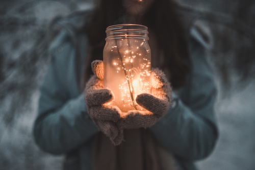Woman facing the camera and holding a mason jar of twinkle lights