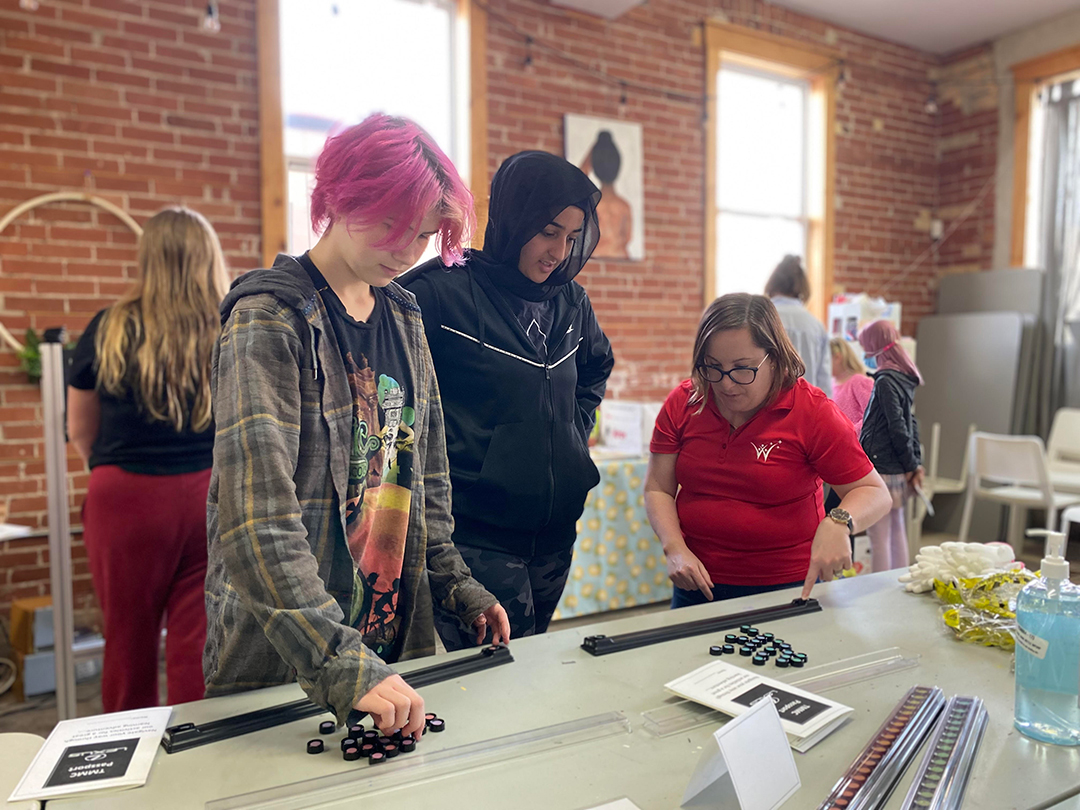 Two participants watch as a woman from Toyota demonstrates an activity