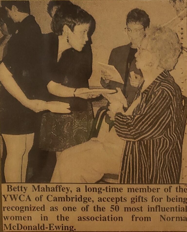 Photograph of an old newspaper clipping, undated. Norma is leaning over and speaking with a long-time member of YWCA Cambridge, Betty Mahaffey