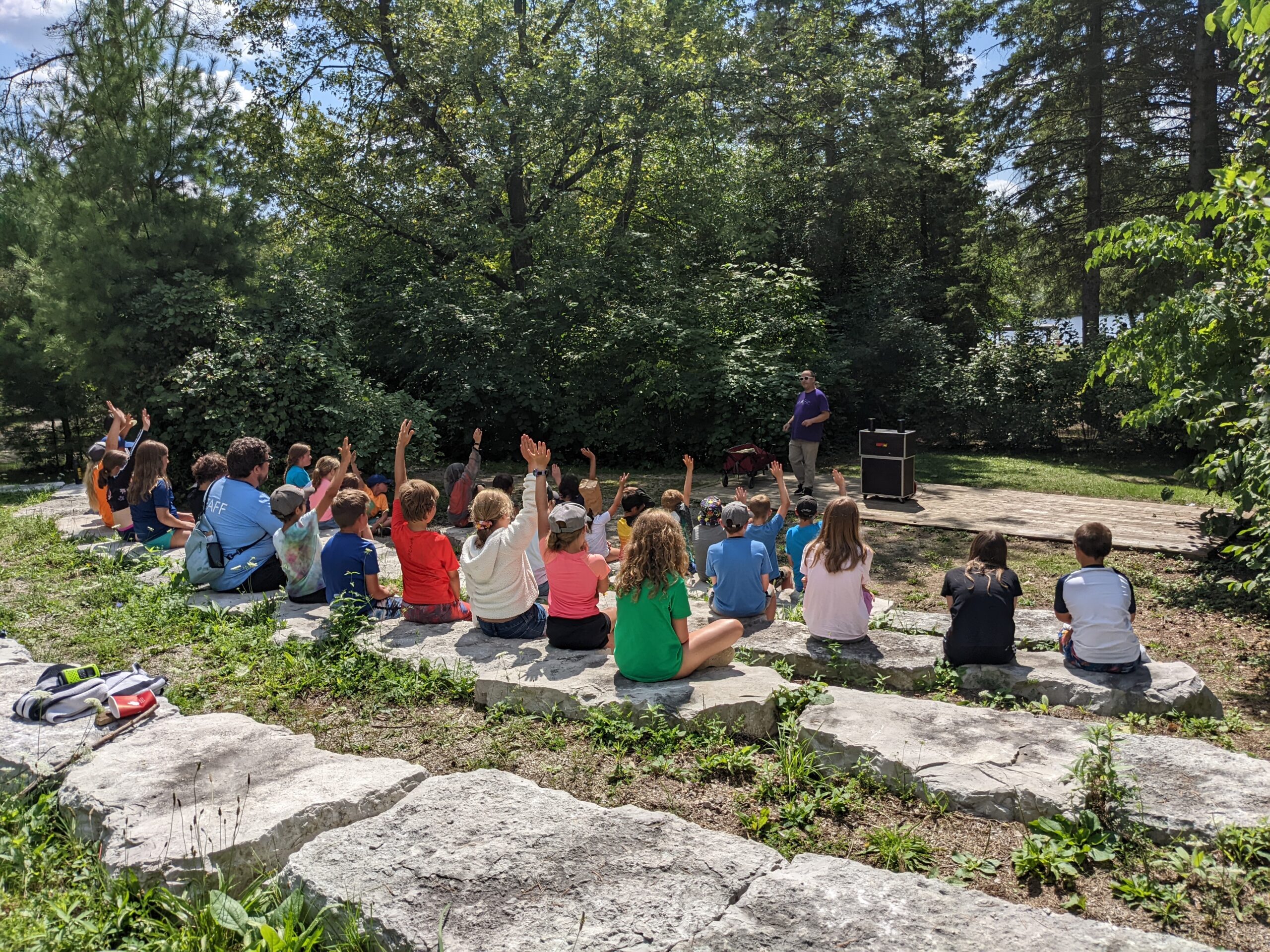 shades mills campers sitting on rocks raising their hands