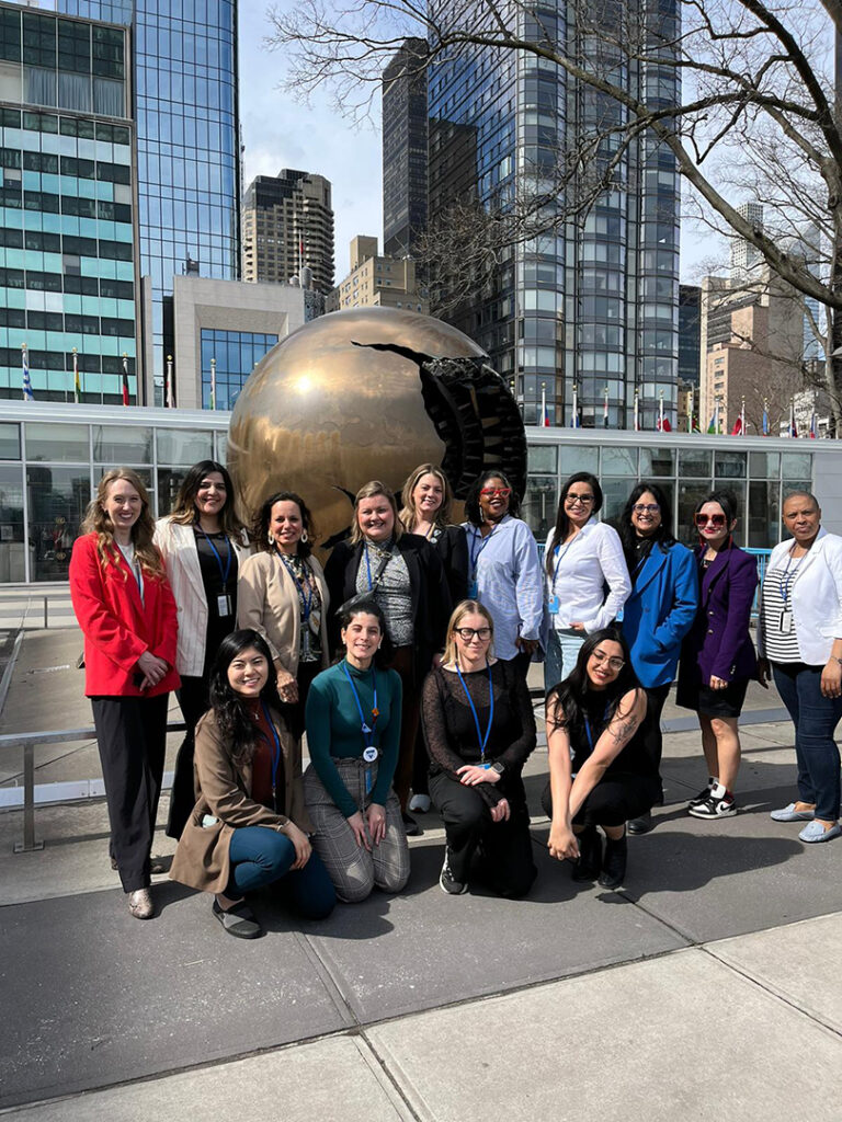 Most of the YWCA Canada delegation stands in front of the iconic globe outside of the United Nations.