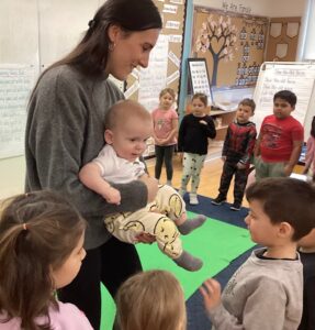 A Roots of Empathy mommy and baby interact with young students during programming,