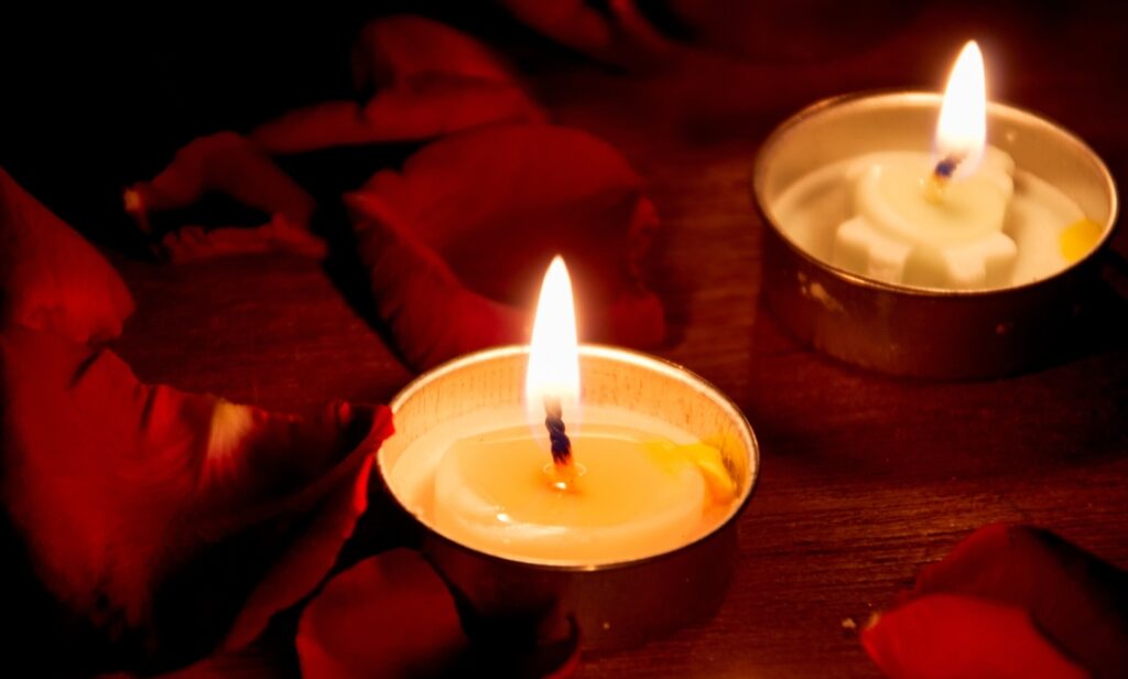 Photo of tealight candles surrounded by dark red rose petals