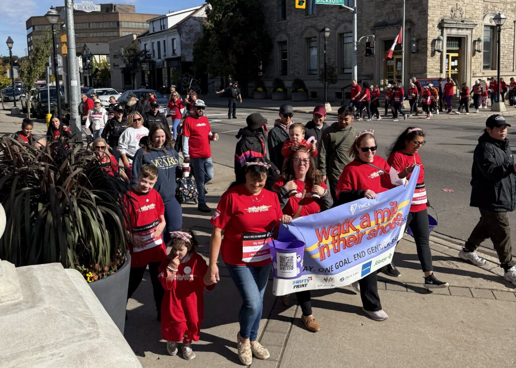 walk a mile participants crossing street and carrying banner