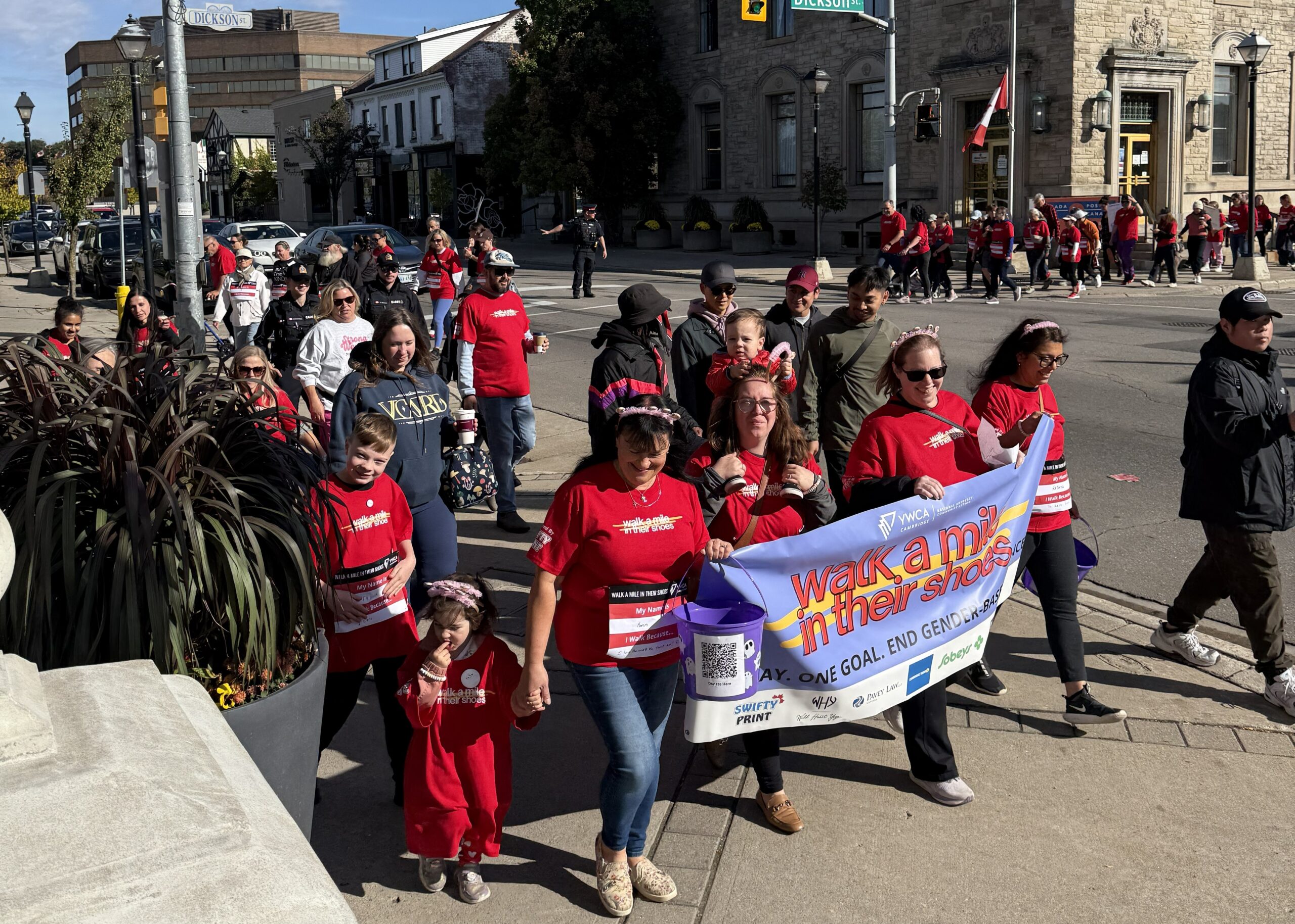 walk a mile participants crossing street and carrying banner