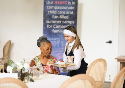 a waiter serves a person in front of a banner in a banquet hall