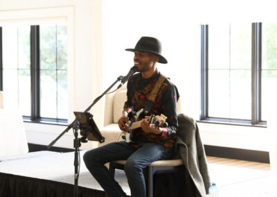 a guitar musician in a large hat sits in front of a stage