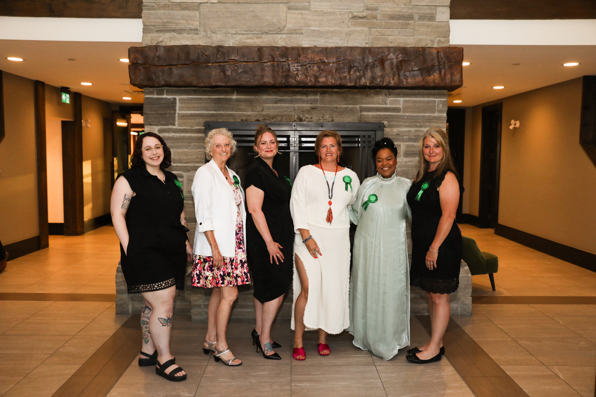 six women stand in a line in front of a fire place.