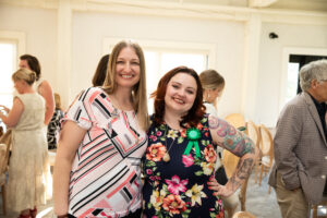 two women stand in a well lit room