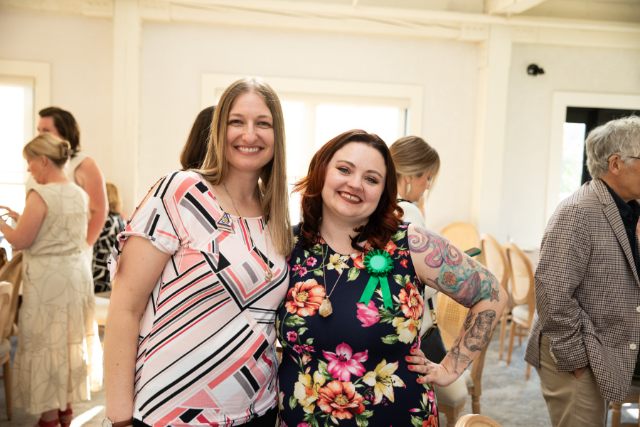 two women stand in a well lit room