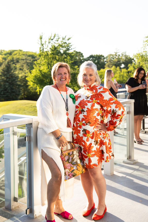 two formally dressed women stand on a deck that backs onto a golf course