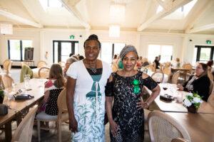 two women with green nominee ribbons stand in a well lit gala room