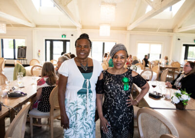 two women with green nominee ribbons stand in a well lit gala room