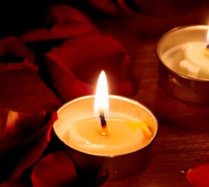 Photo of tealight candles surrounded by dark red rose petals